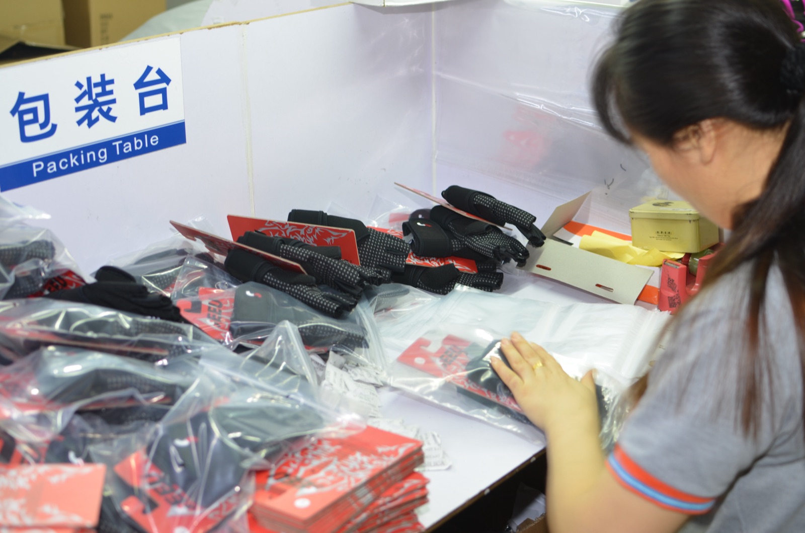 Sports gloves being packed with retail cards and plastic bags at the packing table