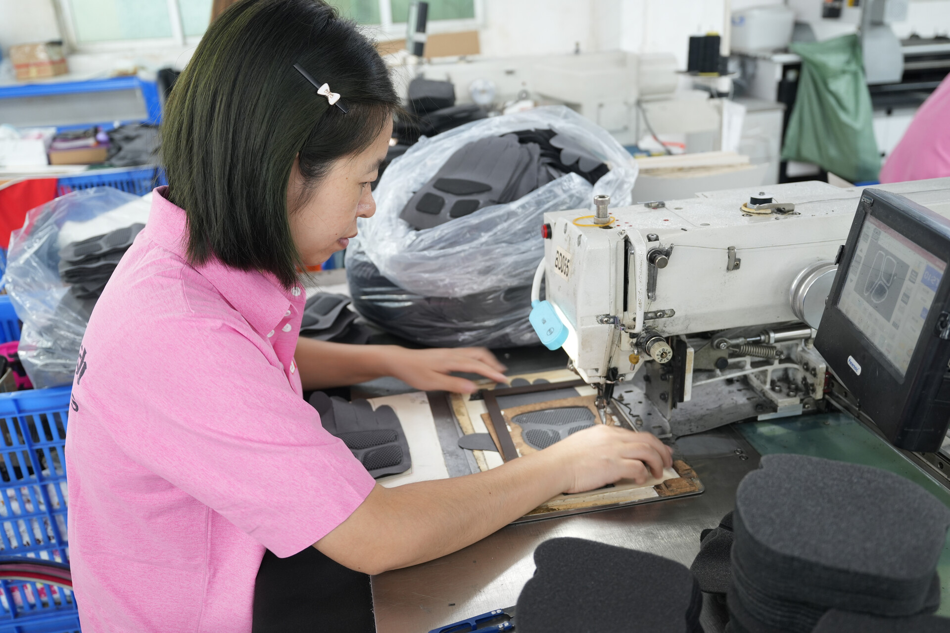 Factory operator preparing sports glove materials at a production workstation