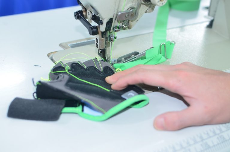 Worker sewing glove panels together on an industrial sewing machine